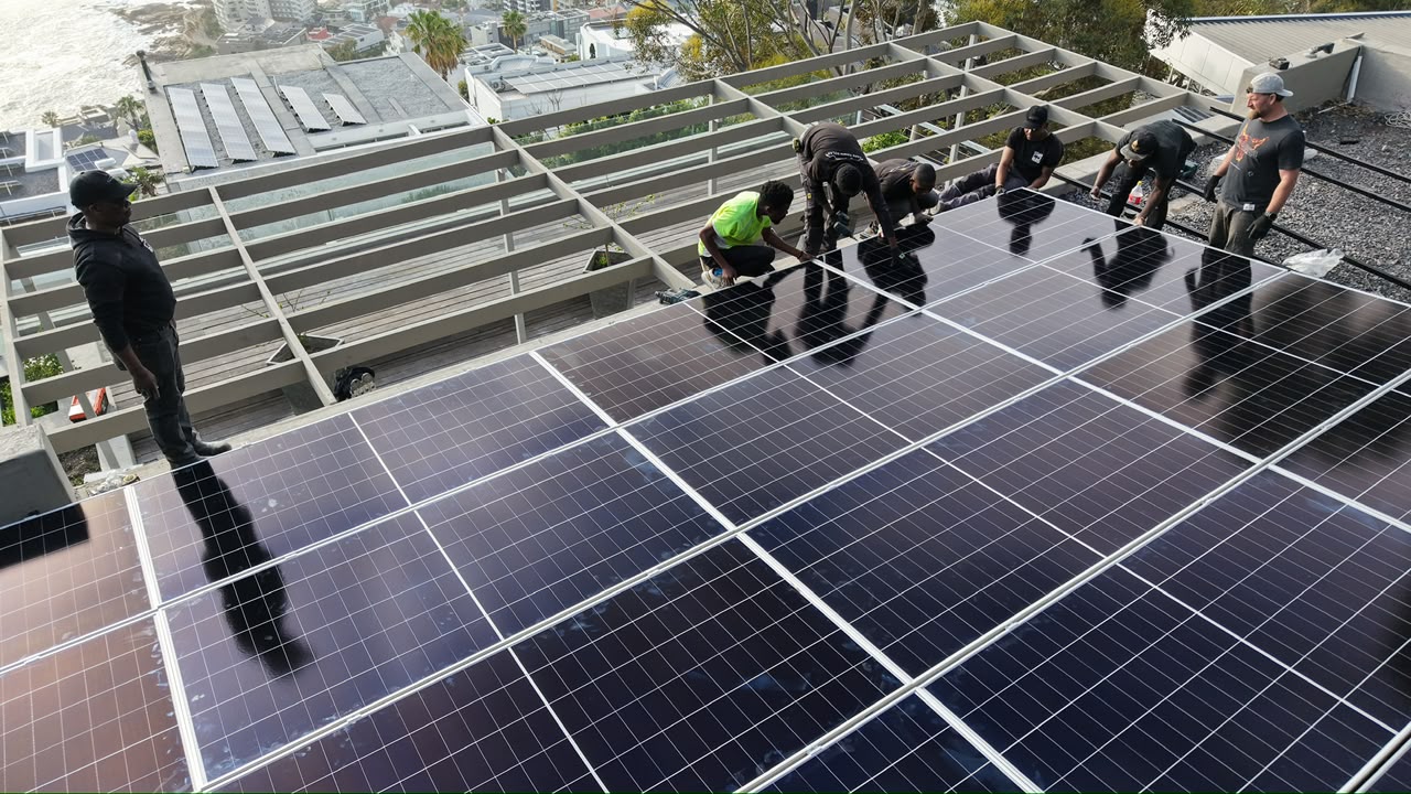 A Sun Savings installer working on a roof against a late afternoon sky